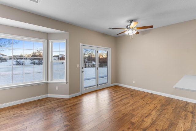 spare room with ceiling fan, a wealth of natural light, and hardwood / wood-style floors