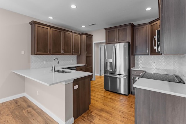 kitchen featuring stainless steel appliances, dark brown cabinetry, sink, light hardwood / wood-style flooring, and tasteful backsplash