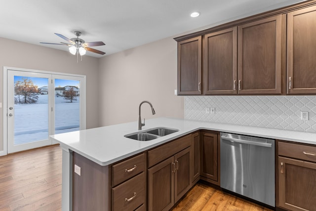 kitchen with stainless steel dishwasher, sink, backsplash, and kitchen peninsula