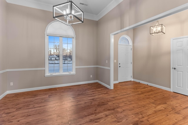 entryway with hardwood / wood-style floors, an inviting chandelier, and crown molding