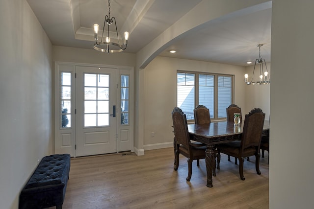 dining space with light hardwood / wood-style floors, a wealth of natural light, and a chandelier