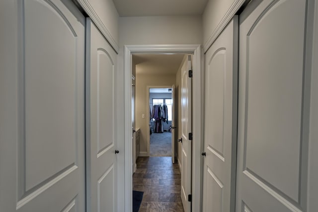 corridor featuring dark colored carpet