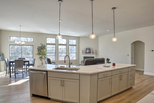 kitchen featuring sink, dishwasher, light hardwood / wood-style flooring, an island with sink, and pendant lighting