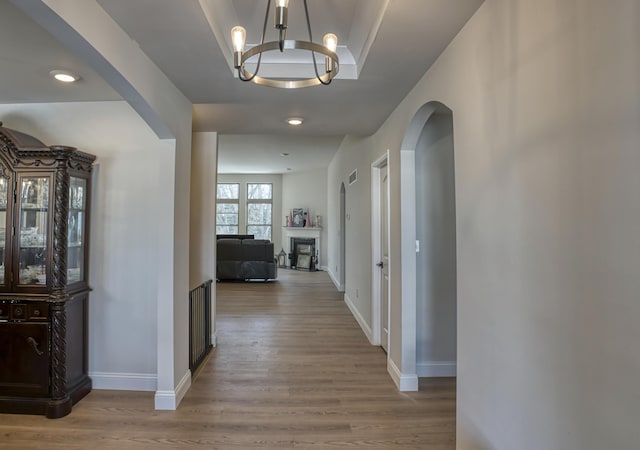 hallway with light wood-type flooring and a notable chandelier