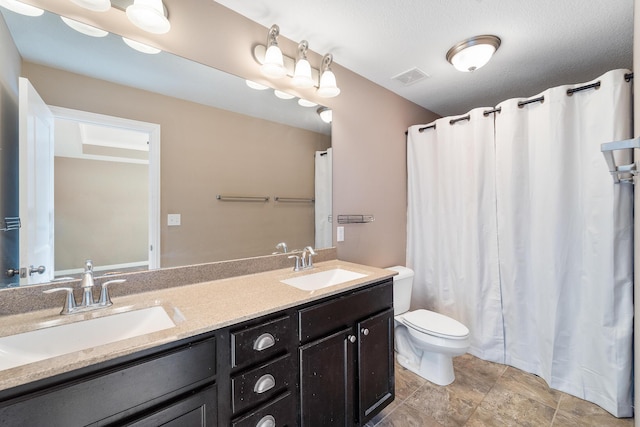 bathroom featuring toilet, vanity, and a textured ceiling