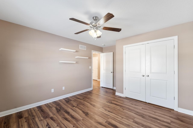 unfurnished bedroom featuring dark wood-type flooring, ceiling fan, and a closet