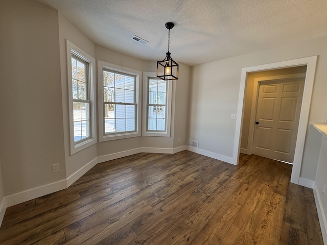 unfurnished dining area with dark wood-type flooring and a textured ceiling