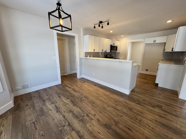 kitchen with dark hardwood / wood-style floors, kitchen peninsula, white cabinetry, and tasteful backsplash