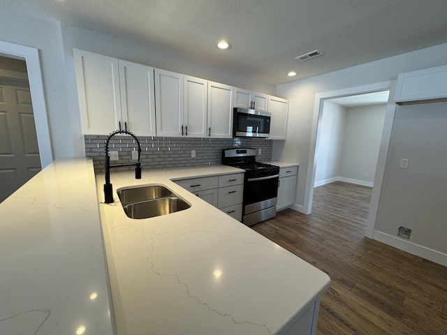 kitchen featuring tasteful backsplash, sink, dark wood-type flooring, stainless steel appliances, and white cabinets