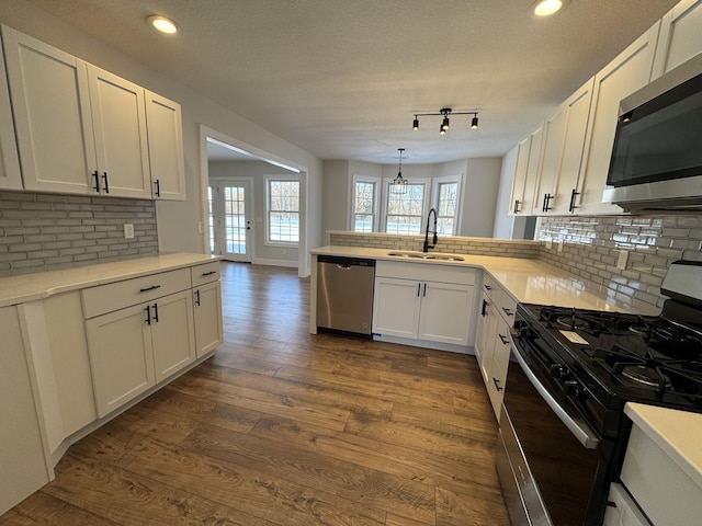 kitchen featuring kitchen peninsula, sink, white cabinetry, hanging light fixtures, and appliances with stainless steel finishes