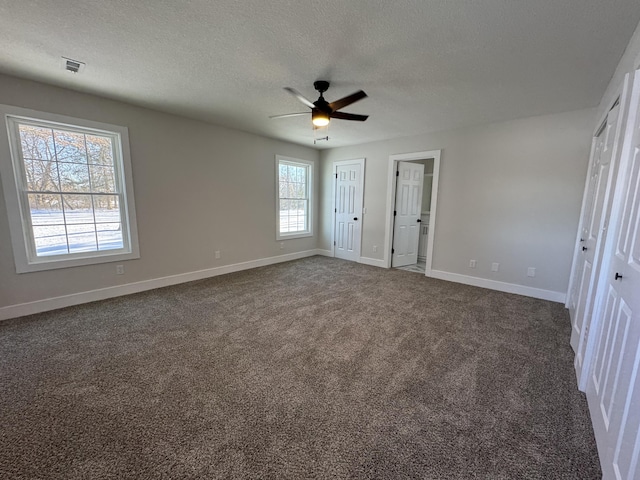 unfurnished bedroom featuring ceiling fan, dark carpet, and a textured ceiling