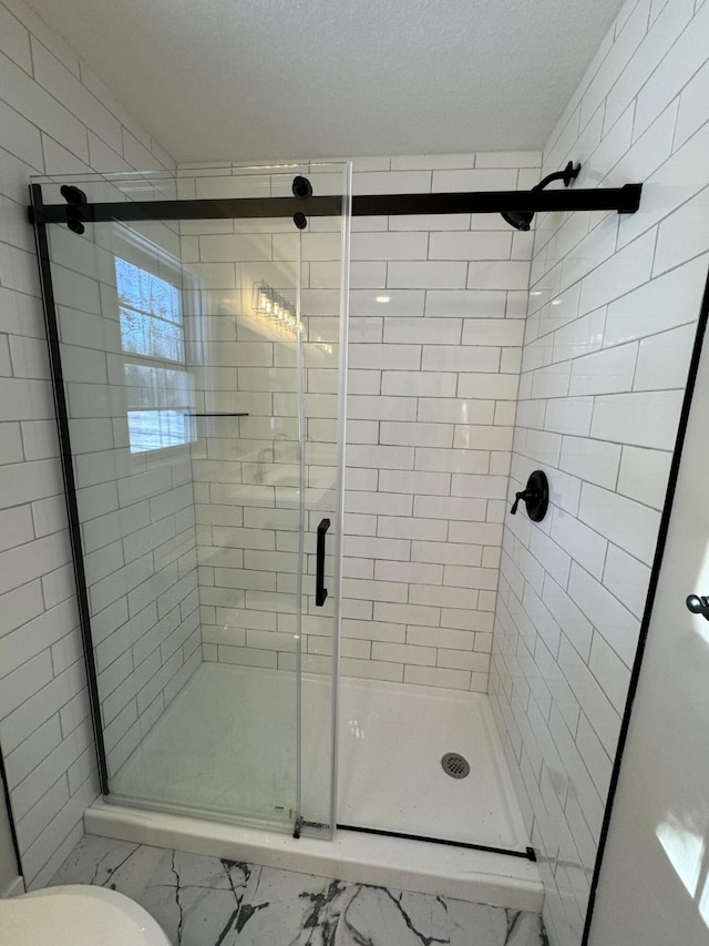 bathroom featuring an enclosed shower and a textured ceiling