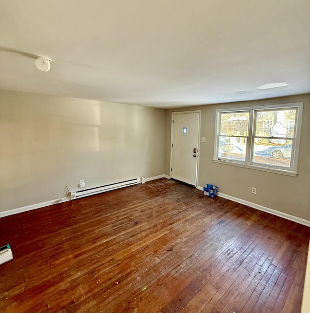 empty room with baseboard heating and dark hardwood / wood-style floors