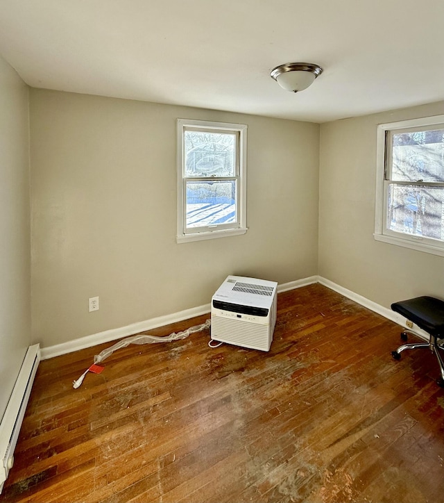 unfurnished room with dark wood-type flooring, a baseboard radiator, a healthy amount of sunlight, and heating unit