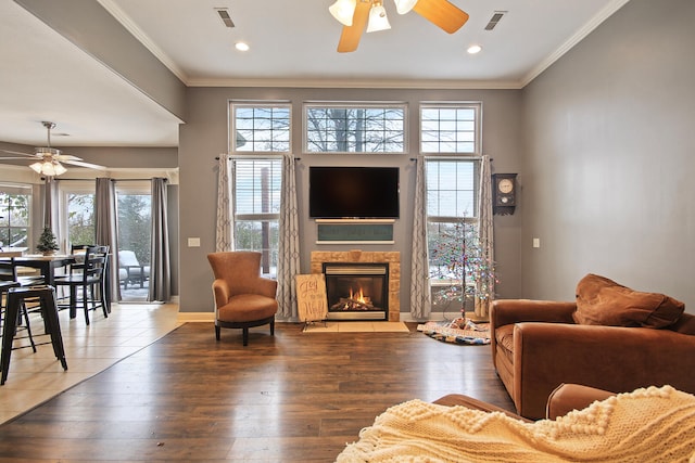 living room featuring ornamental molding, hardwood / wood-style flooring, and a stone fireplace