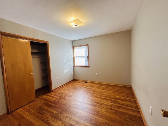 unfurnished bedroom featuring a closet and dark hardwood / wood-style flooring