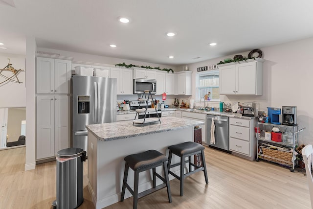 kitchen featuring a kitchen bar, sink, white cabinetry, a center island, and stainless steel appliances