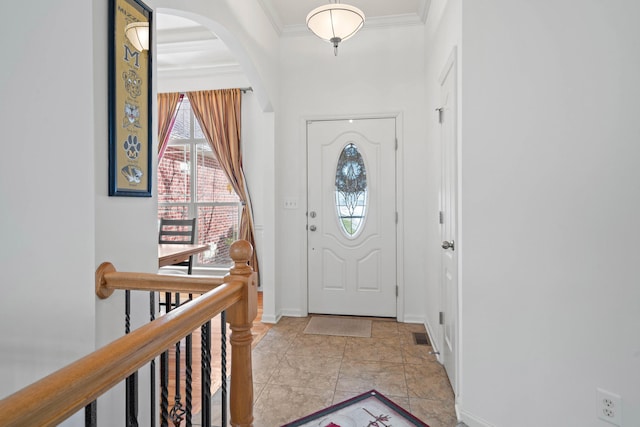 foyer entrance featuring baseboards, ornamental molding, and arched walkways