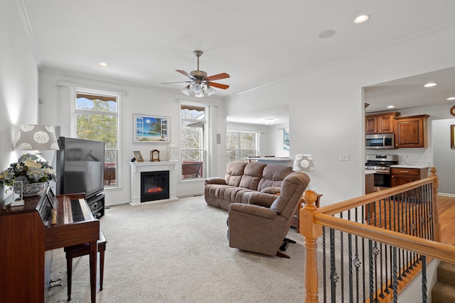 living room with a healthy amount of sunlight, a glass covered fireplace, and crown molding