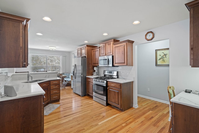 kitchen featuring stainless steel appliances, tasteful backsplash, light wood-type flooring, and a sink