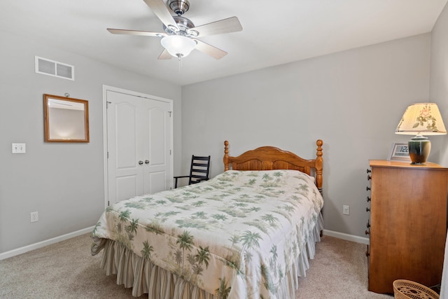 bedroom with a closet, light colored carpet, visible vents, a ceiling fan, and baseboards