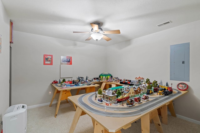 recreation room with ceiling fan, a textured ceiling, and electric panel