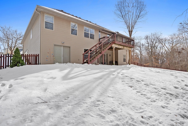 snow covered back of property featuring a deck