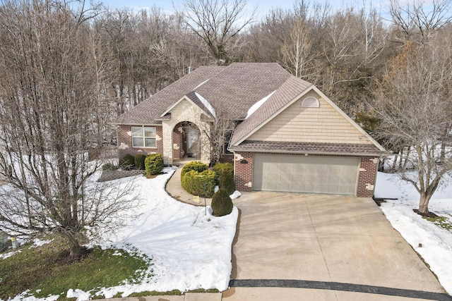 view of front of home with driveway, brick siding, roof with shingles, and an attached garage