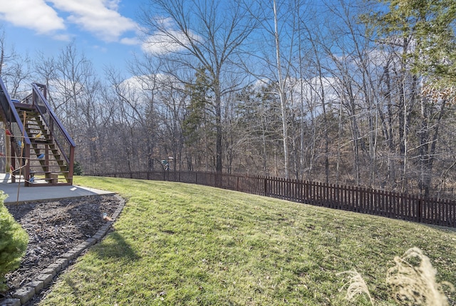 view of yard with stairway, a patio area, fence, and a wooded view