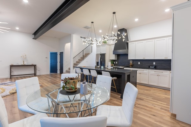 dining room featuring a chandelier, light hardwood / wood-style floors, and beamed ceiling