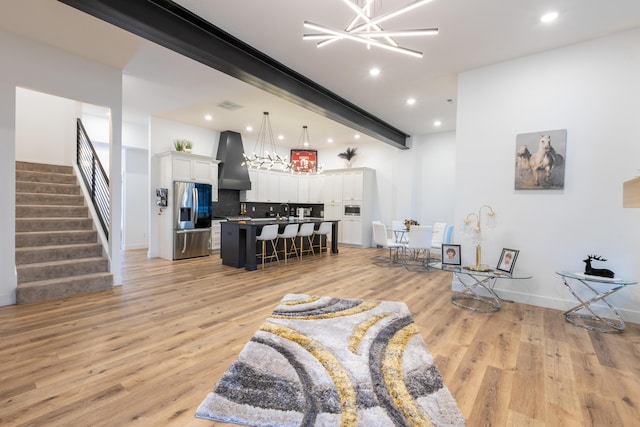 living room featuring a chandelier, light hardwood / wood-style flooring, sink, and beamed ceiling