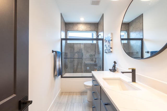 full bathroom with combined bath / shower with glass door, vanity, and toilet