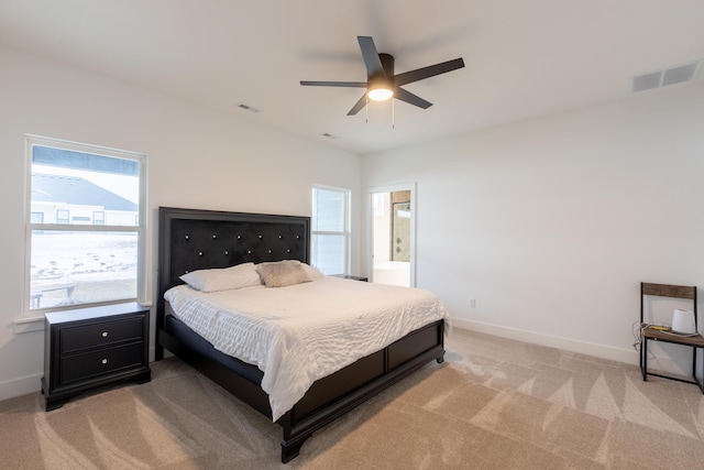 bedroom featuring ceiling fan, ensuite bathroom, and light carpet