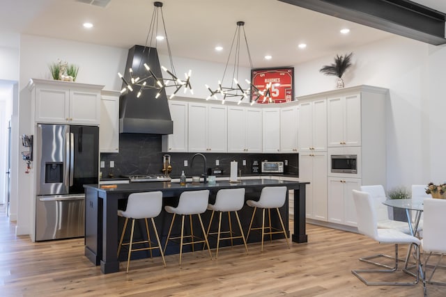 kitchen featuring a kitchen bar, white cabinetry, hanging light fixtures, a kitchen island with sink, and appliances with stainless steel finishes