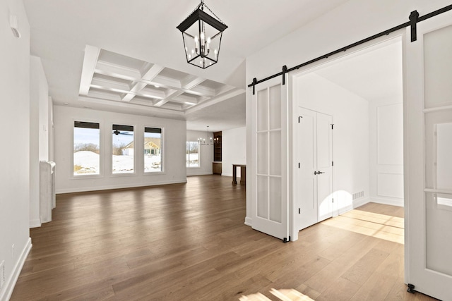 interior space featuring a barn door, a notable chandelier, beam ceiling, wood-type flooring, and coffered ceiling