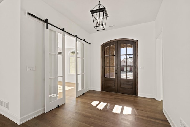 foyer entrance with french doors, a notable chandelier, and dark hardwood / wood-style floors