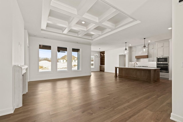 unfurnished living room with dark wood-type flooring, coffered ceiling, an inviting chandelier, and beamed ceiling