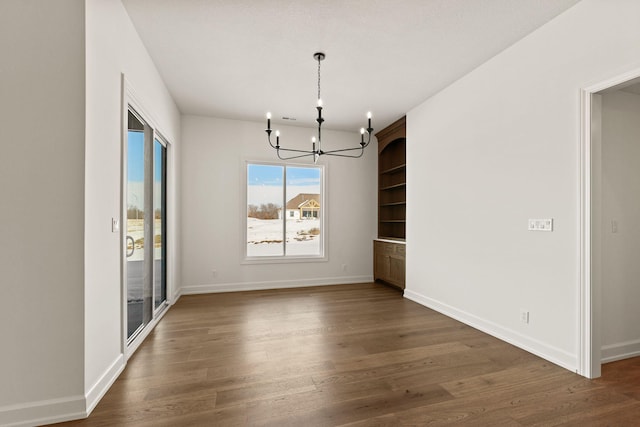 unfurnished dining area featuring dark hardwood / wood-style floors and an inviting chandelier