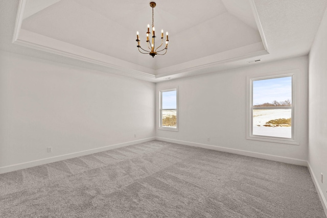 empty room featuring carpet flooring, a raised ceiling, and a notable chandelier