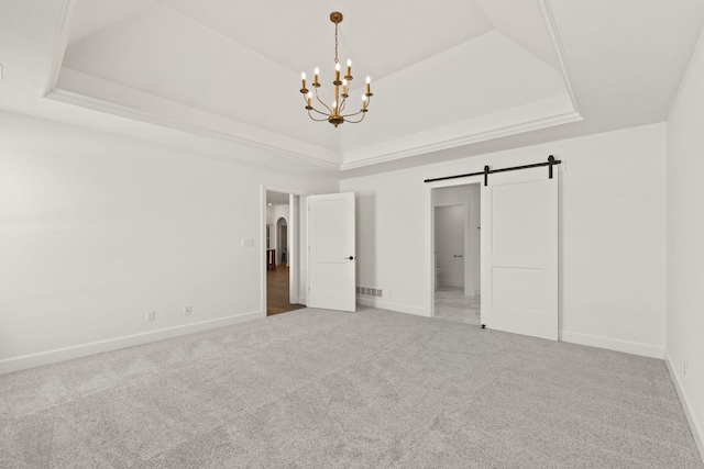 unfurnished bedroom featuring a chandelier, carpet, a raised ceiling, and a barn door