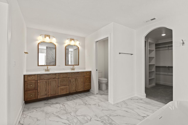 bathroom featuring a bath, toilet, and vanity