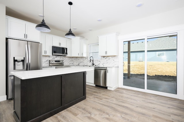 kitchen with white cabinets, a kitchen island, stainless steel appliances, and backsplash