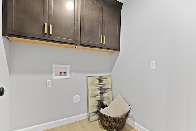 clothes washing area featuring washer hookup, cabinet space, light wood finished floors, and baseboards