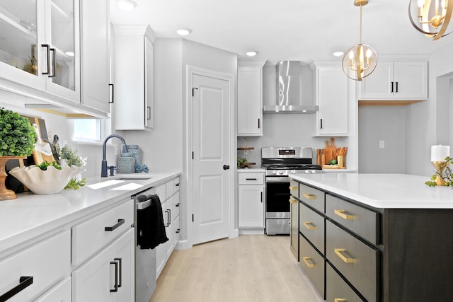 kitchen with white cabinets, wall chimney exhaust hood, hanging light fixtures, stainless steel appliances, and light countertops