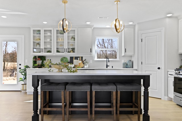 kitchen with glass insert cabinets, white cabinetry, visible vents, and a breakfast bar