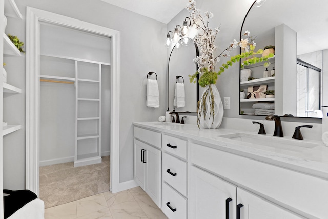 bathroom with double vanity, a shower stall, a walk in closet, and a sink