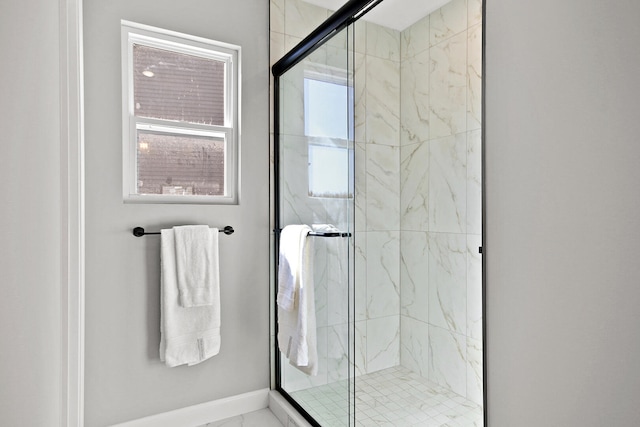 bathroom featuring a marble finish shower and baseboards