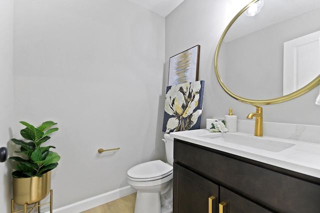 half bathroom featuring wood finished floors, vanity, toilet, and baseboards