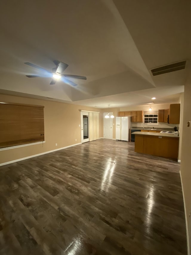 unfurnished living room with dark wood-type flooring and ceiling fan with notable chandelier