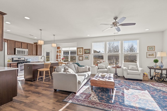 living room with dark wood-type flooring, sink, and ceiling fan